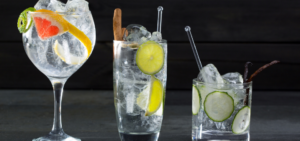 Three different shaped glasses of gin and tonic set against a black background.